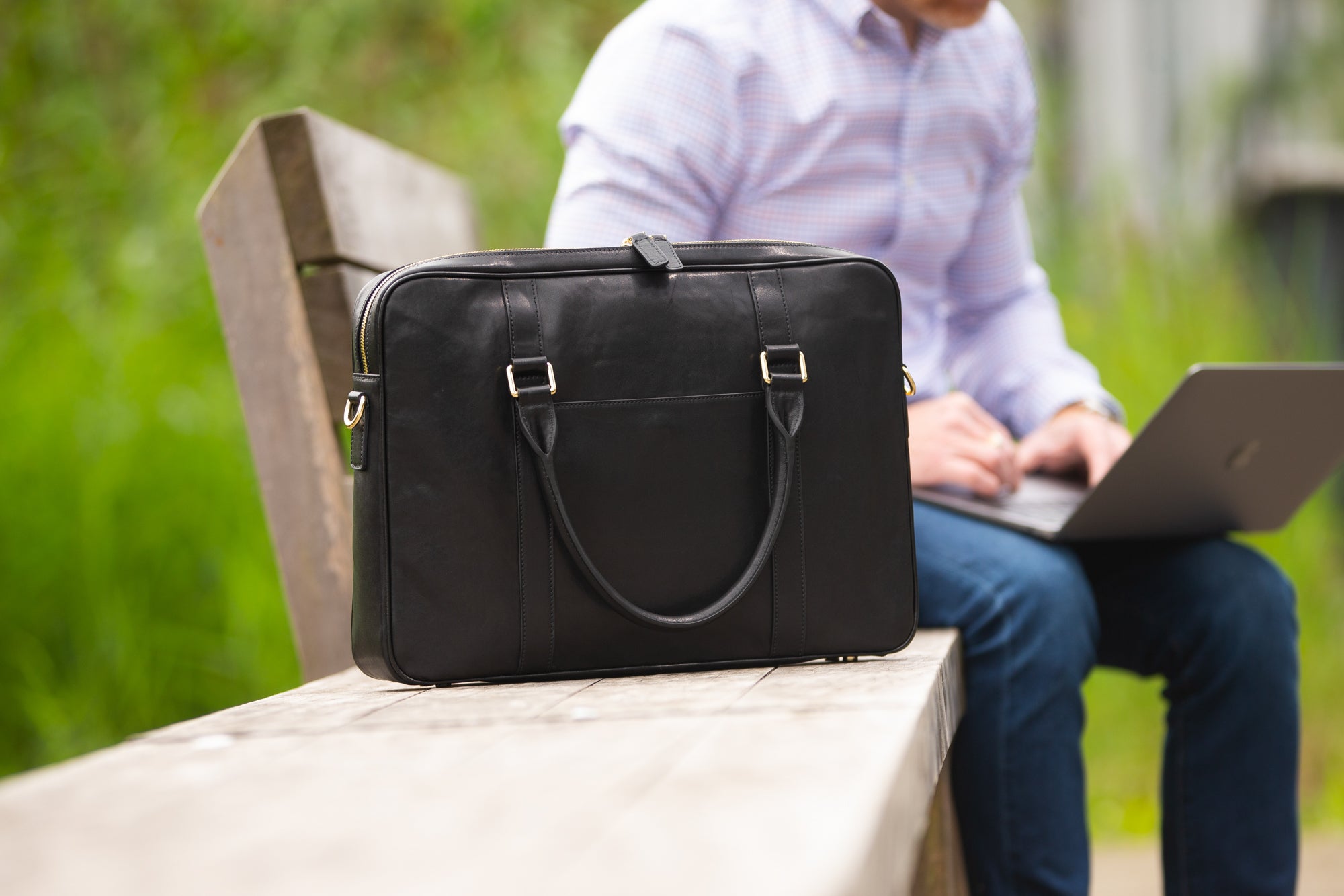 Black full grain vegetable tanned leather briefcase on a park bench